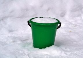 zelený kyblík plný sněhu na sněhu