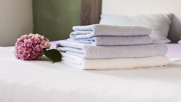 Ručníky poskládané na posteli a ozdoba hortenzie