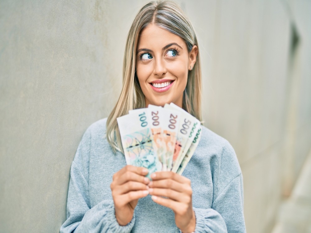 Usměvavá žena s českými bankovkami